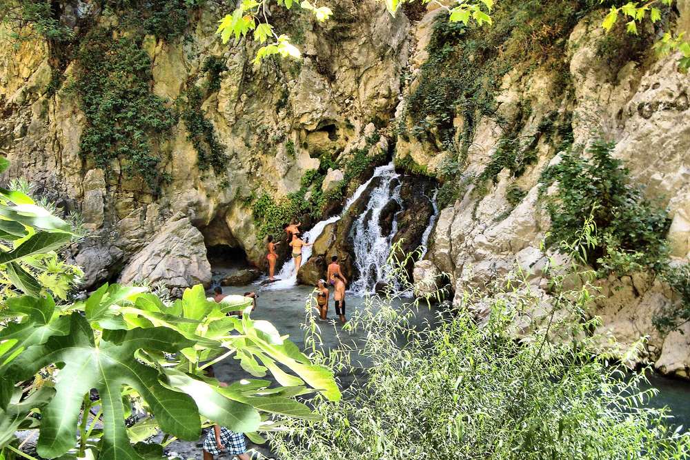 Visitors crossing the hanging wooden boardwalk over the Eşen stream at the entrance to Saklıkent Gorge
